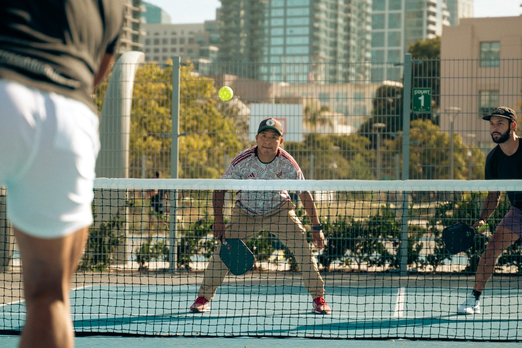 Players across the net in an open pickleball game on an outdoor urban court