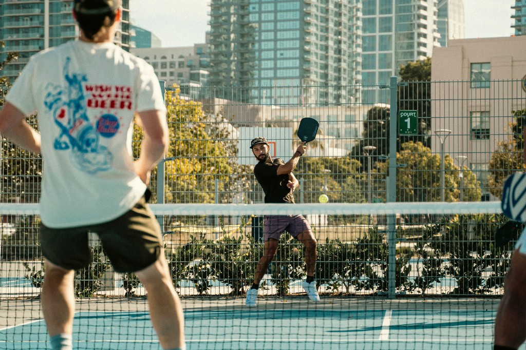 A player swinging through a pickleball rally on an outdoor court