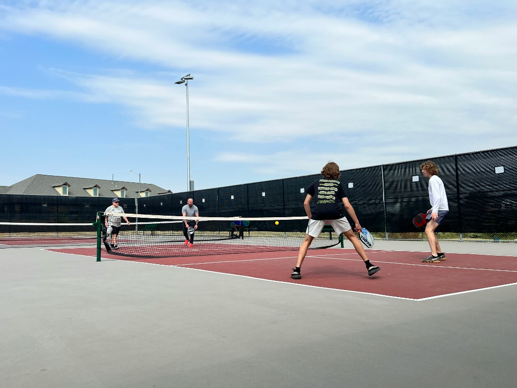 Four players in a doubles pickleball match on an outdoor tournament court